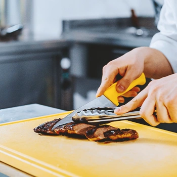 A chef cutting up steak in a kitchen