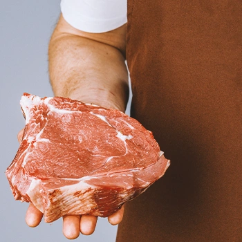 A person holding raw meat on his right hand