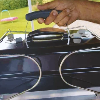 A person holding a portable grill