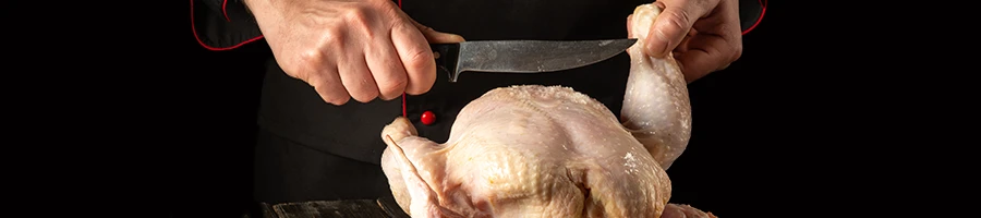 A man slicing a chicken using a knife