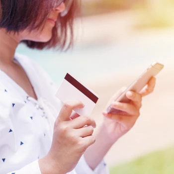 A woman holding a phone and a credit card