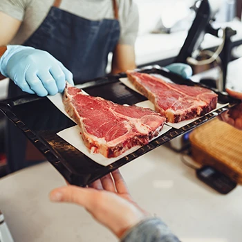 A butcher serving two slices of raw meat