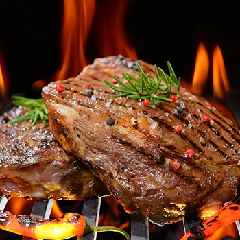 A roast beef on top of a flaming grill