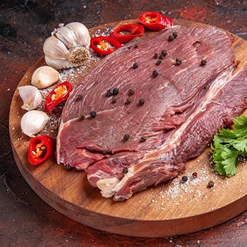 A huge chunk of meat on a cutting board with different spices