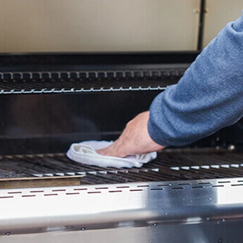 A person cleaning the grills of a smoker