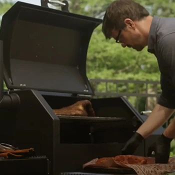 A man putting a large meat inside a smoker