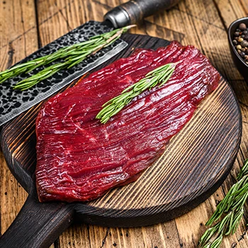 A raw elk steak on a cutting board