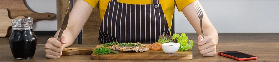 An image of a woman ready to eat while holding a knife and fork