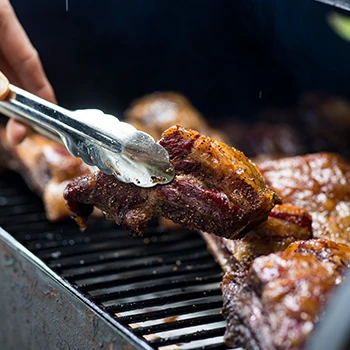 A person putting a meat inside a smoker