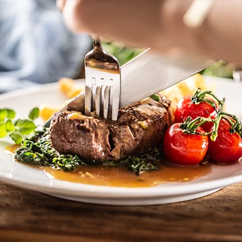 A person slicing a meat on a plate