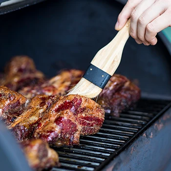 A person brushing a marinade on a meat inside a smoker