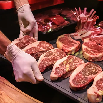 A person holding a plate full of raw steaks