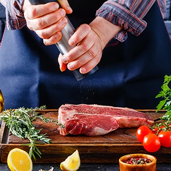 A person pouring salt in large piece of meat