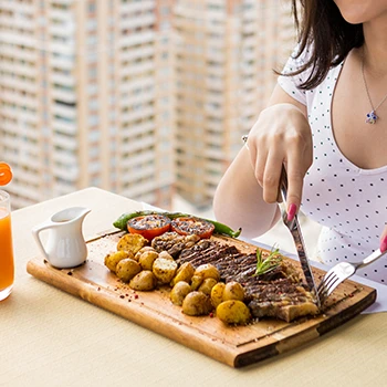 A person eating steak and potatoes