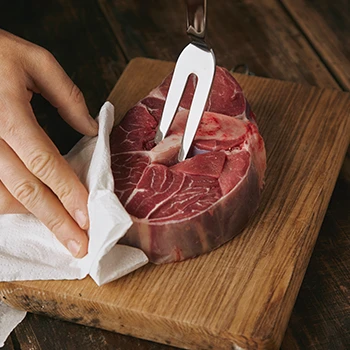 A guy holding a meat using a fork