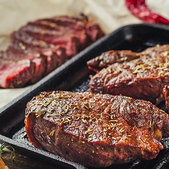 An image of whole steak on a pan and sliced steak on the side