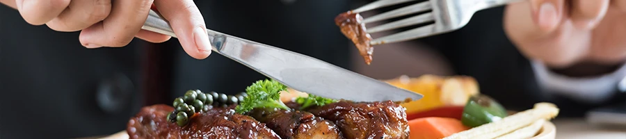 A person who is about to eat while holding a knife and a fork