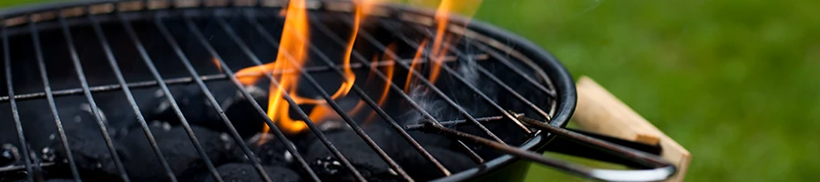 A close up image of a charcoal grill with flames