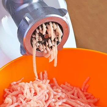 A close up image of meat grinder and a bowl of ground meat