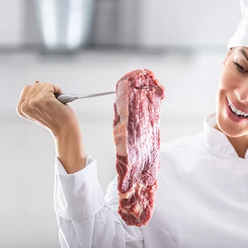 A chef lifting a piece of meat using a knife