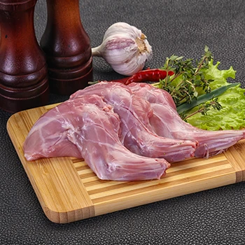 A rabbit meat on top of a chopping board with different spices on the side