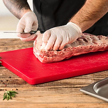 A person wearing gloves removing the skin of a meat