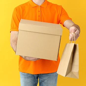 A person holding a box and a paper bag