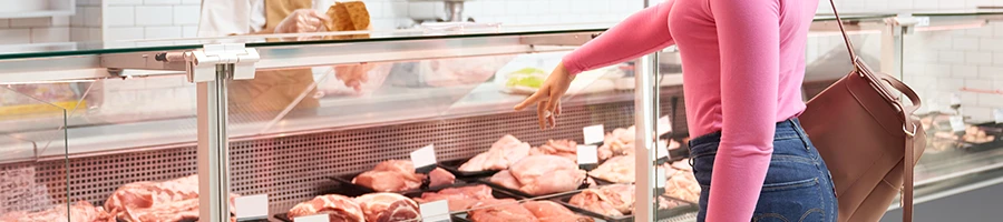 A woman pointing a meat in a grocery