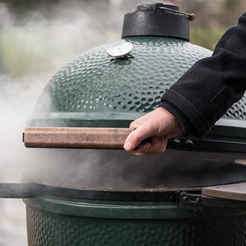 A person opening the lid of a smoker