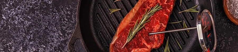 A steak on a pan with thermometer