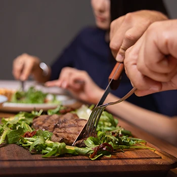 Two people eating steak on a cutting board