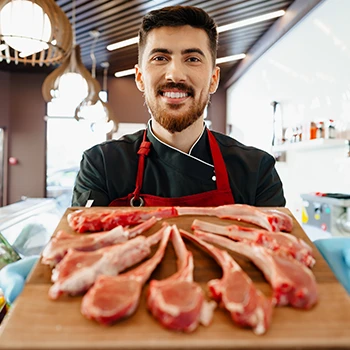 A butcher holding a cutting board with slices of meat