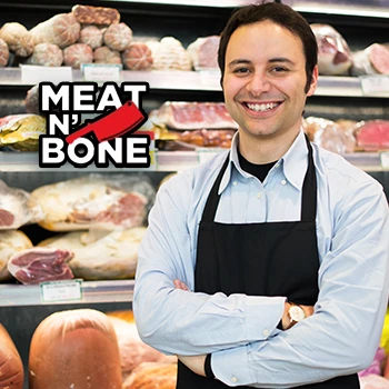 A guy smiling in front of different meats