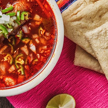 A top view of a menudo and tortillas