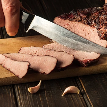 A person slicing a well-done steak