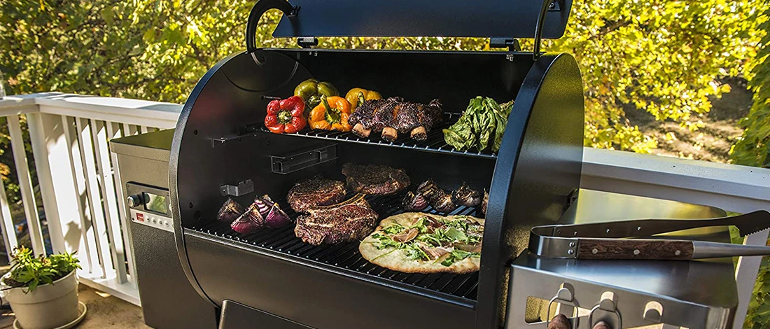An outdoor image of a smoker grill full of different foods