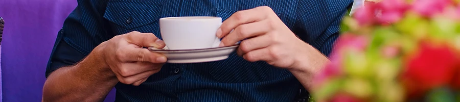 A close up image of a guy holding a cup of beverage