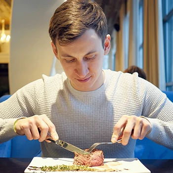 A guy slicing a steak on a plate