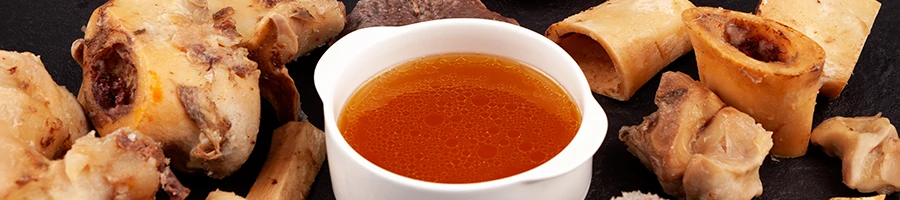 An image of bone broth in a bowl with bones on the side