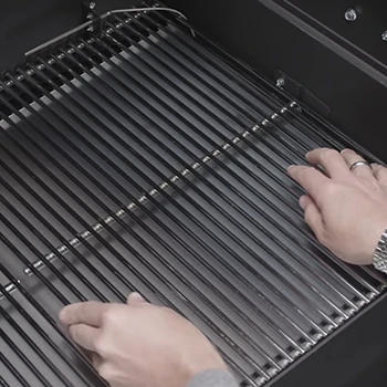 A person placing a metal grill in a smoker