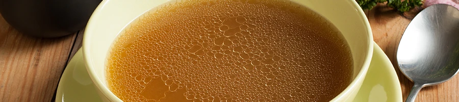 An image of a bone broth in a bowl with spoon on the side