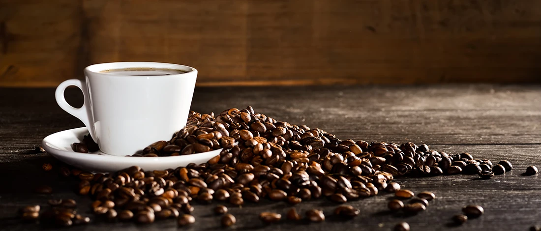 An image of a cup of coffee and coffee beans