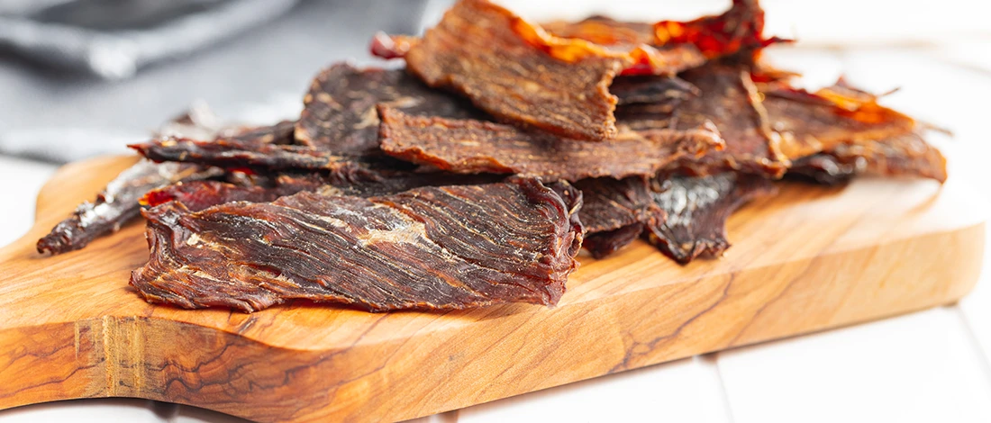 An image of beef jerky on a wooden board