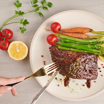 A woman slicing a cooked meat on a plate