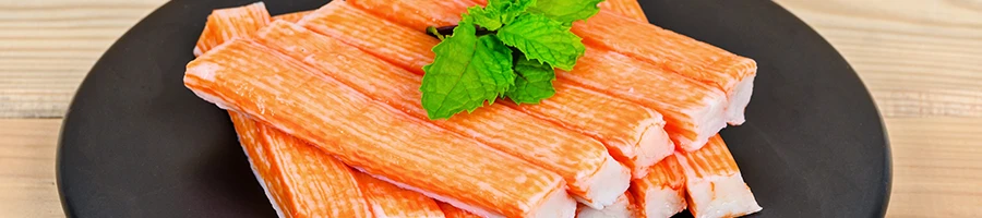 A close up image of imitation crab meat on a black plate