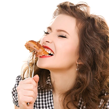 A woman biting meat on a fork