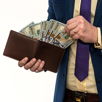 A person wearing a suit pulling out money from a wallet