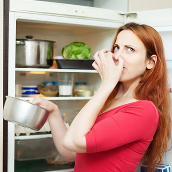 A woman holding her nose because of smelly food