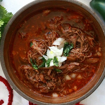 An image of birria meat with sliced onions on top