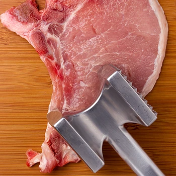 A top view image of meat and meat mallet
